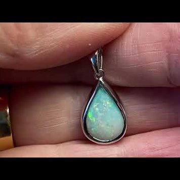 Vedhæng med en ægte solid krystal opal fra Australien indfattet i blankt rhodineret sterling sølv.