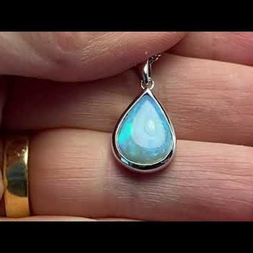 Vedhæng med en ægte solid krystal opal fra Australien indfattet i blankt rhodineret sterling sølv.