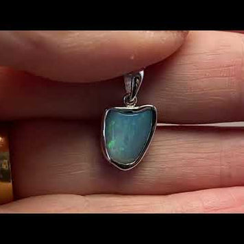Vedhæng med en ægte solid krystal opal fra Australien indfattet i blankt rhodineret sterling sølv.