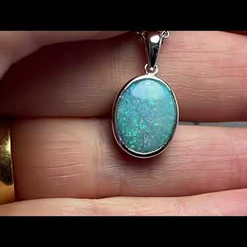 Vedhæng med en ægte solid krystal opal fra Australien indfattet i blankt rhodineret sterling sølv.