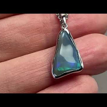Vedhæng med en ægte solid krystal opal fra Australien indfattet i blankt rhodineret sterling sølv.