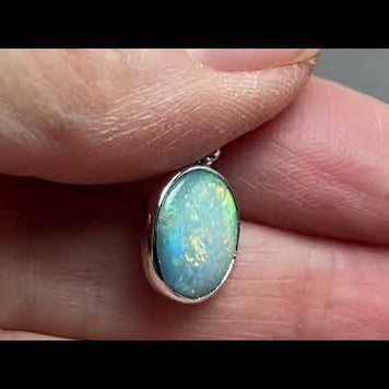 Vedhæng med en ægte solid krystal opal fra Australien indfattet i blankt rhodineret sterling sølv.